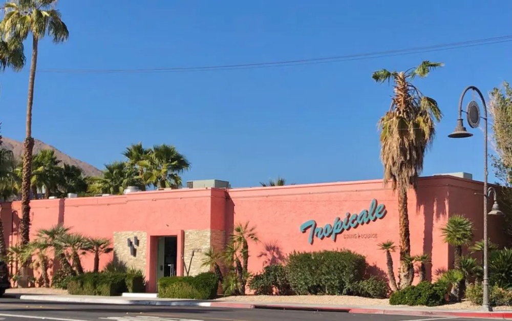 a street lined with palm trees and a building in the background