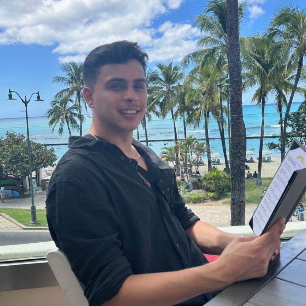 a man holding a laptop and smiling at the camera