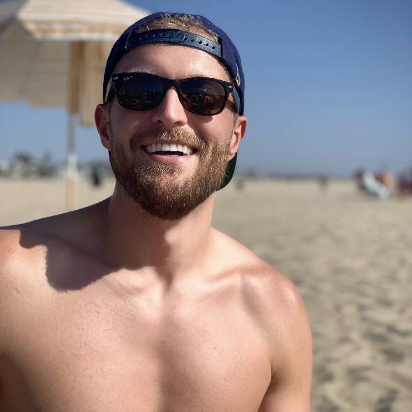 a man wearing sunglasses and standing in front of a beach